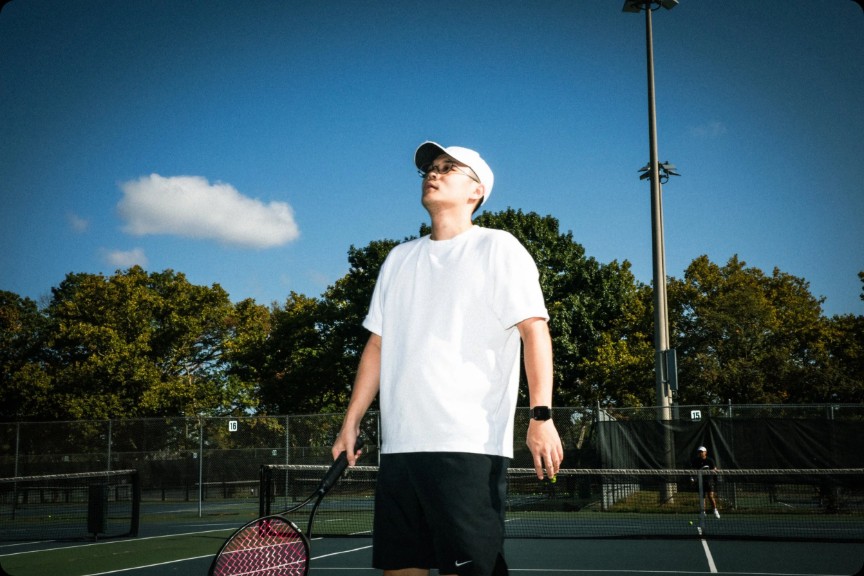 Matt standing on court looking up at the sky, racket at his side