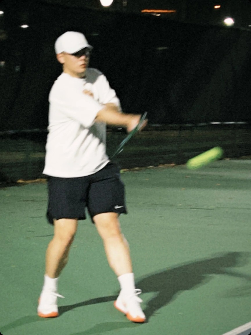 Matt hitting a backhand under indoor court lights at night