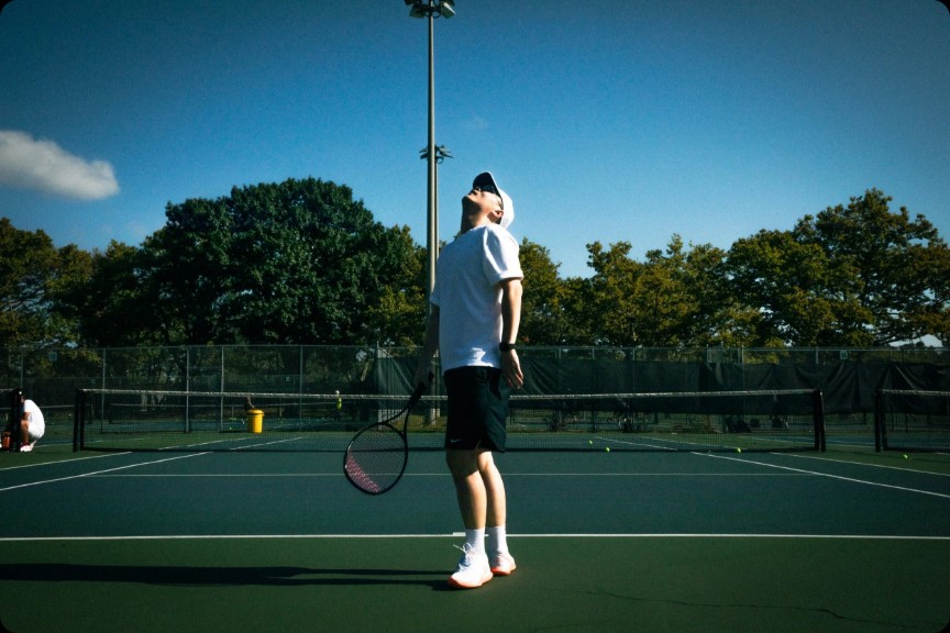 Matt looking upward before a serve on an outdoor court