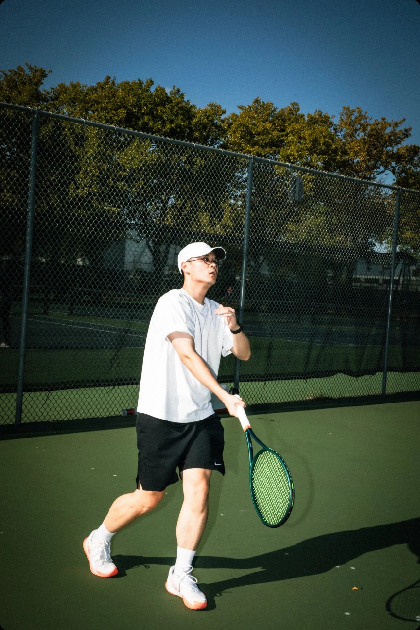 Matt in ready position holding a green racket on a sunny court